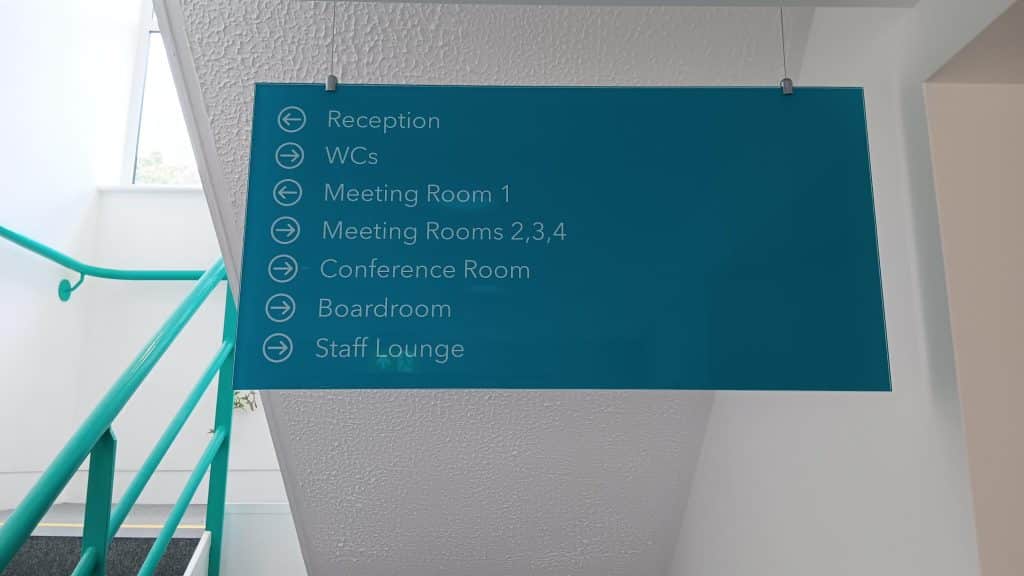A teal office sign directing visitors and staff to various rooms