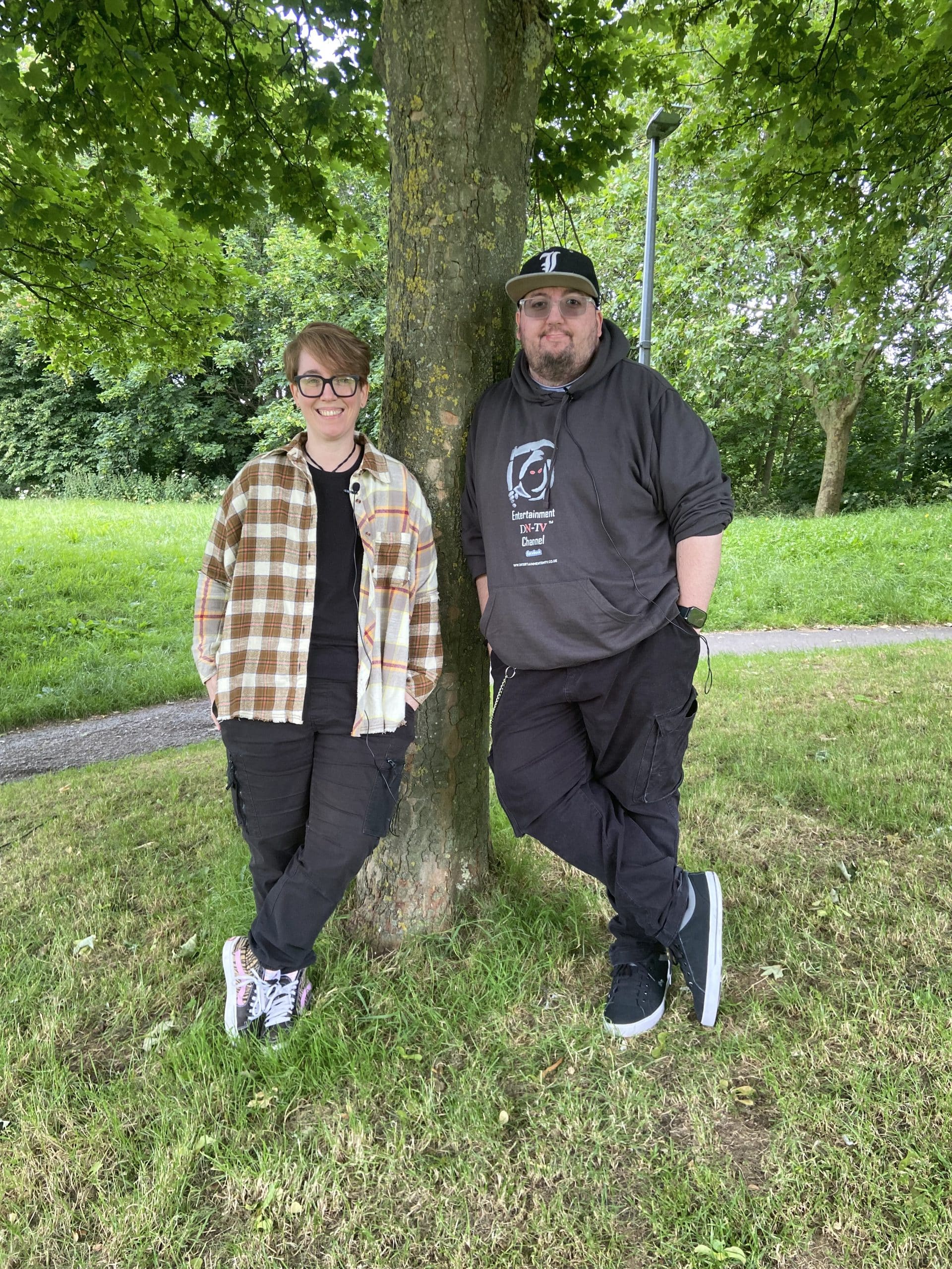 Ezra and Drew standing together by a tree in a park.