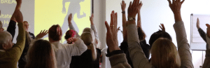 People in a conference with their hands raised