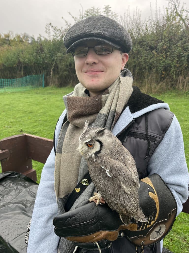 A young man with a small grey owl on his arm