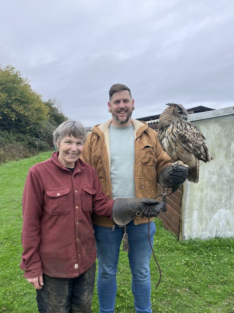 Woman and man holding a large owl