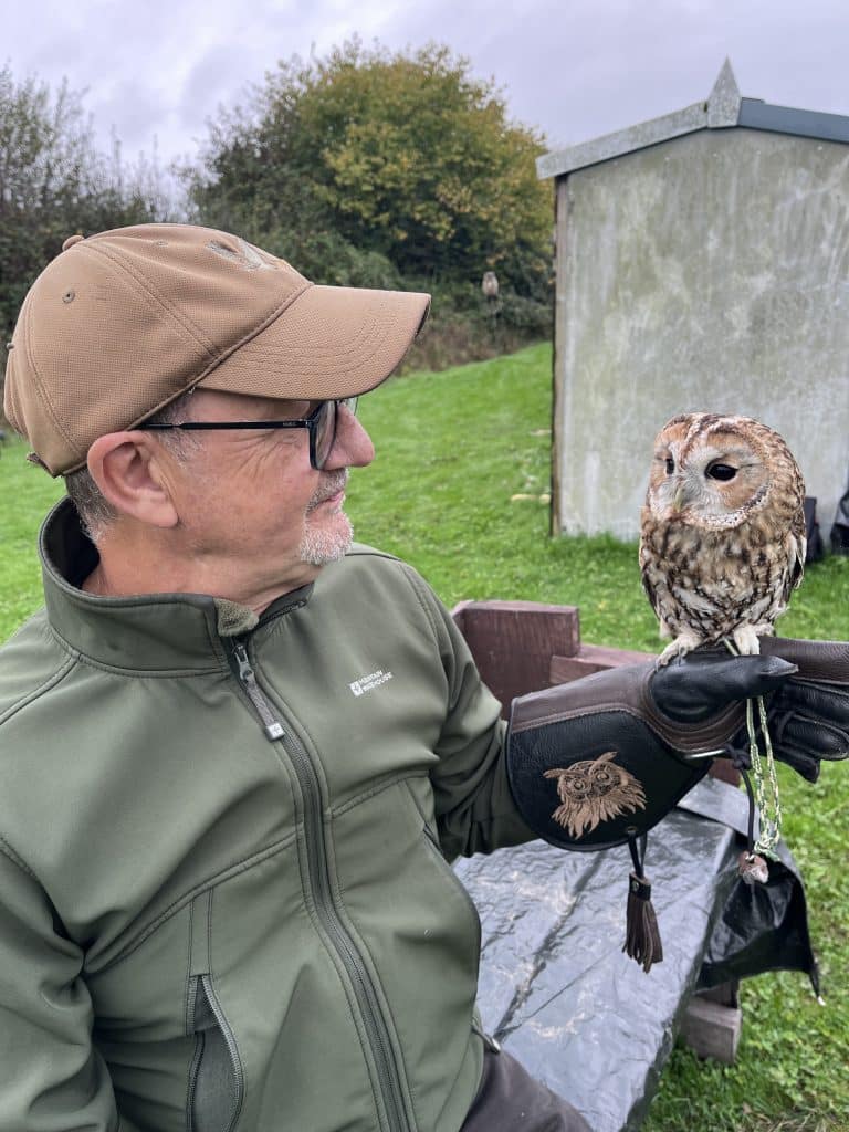 Man in glasses and a cap holding an owl