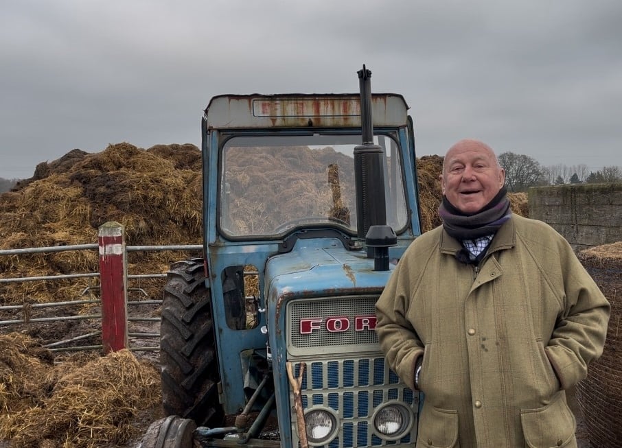 Older man standing by a tractor at a farming group to help men's mental health