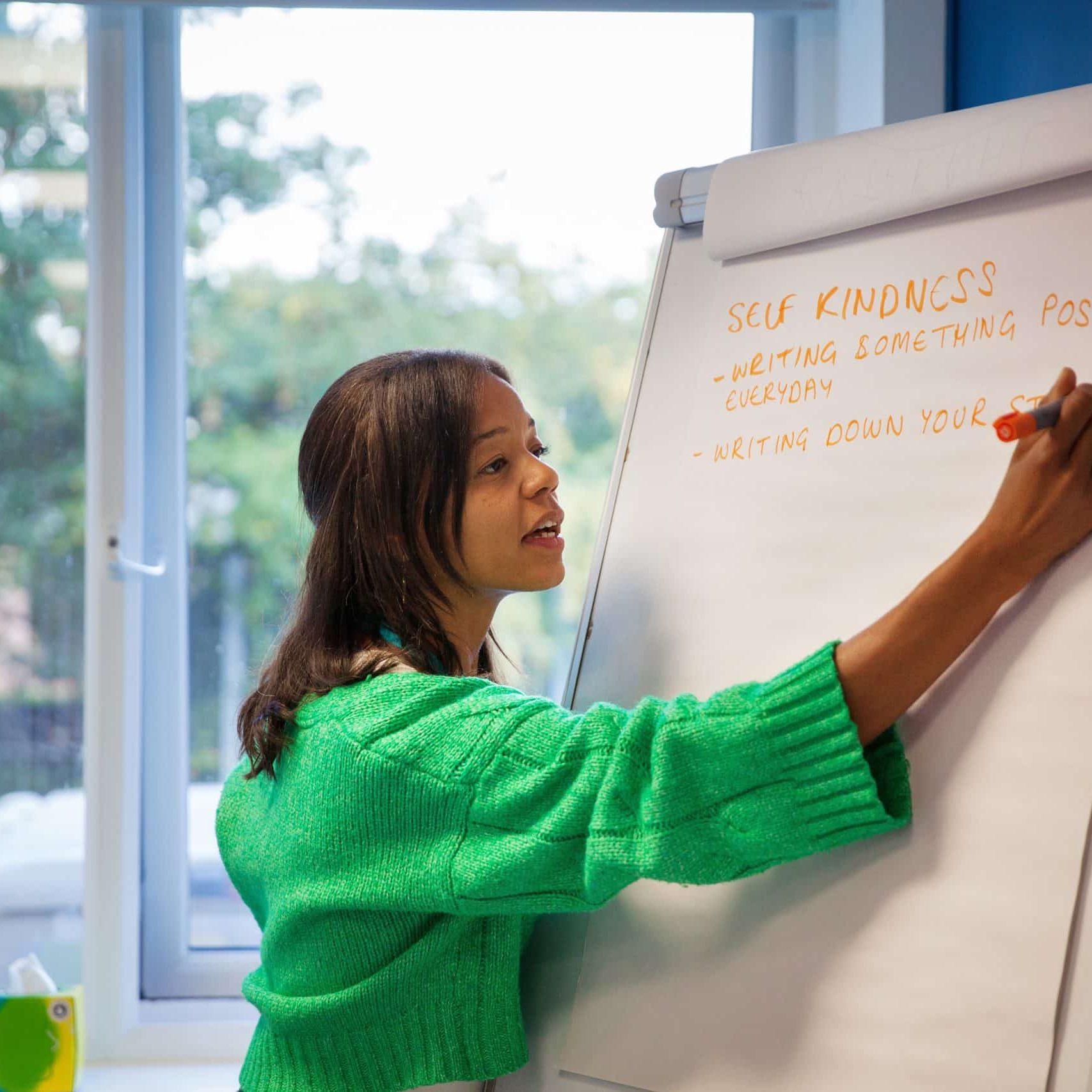 Bristol Wellbeing Tutor Jas writing on a flipboard